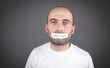 © andranik123 - Man covering his mouth with a Human Rights text on torn paper.