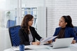 © DragonImages - Female business partners discussing contract details before signing papers at meeting