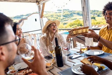 Group of friends at reunion eating and drinking wine.