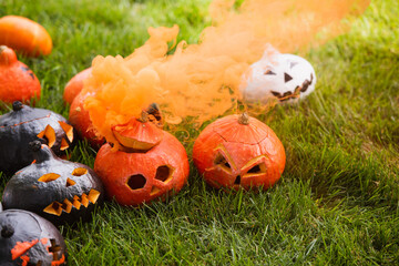 Poster - carved and spooky pumpkins with orange smoke on green lawn