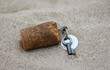 Ein Schlüssel für ein Schloss, Vorhängeschloss mit Korkanhänger liegt im Sand.
