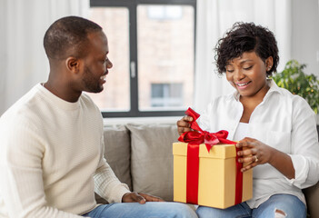 Wall Mural - holidays, celebration and people concept - happy african american couple with christmas gift at home