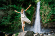 Woman standing in a yoga pose in front of a waterfall in the jungle