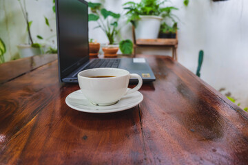 Wall Mural - Coffee cup and laptop on a wooden table in the garden