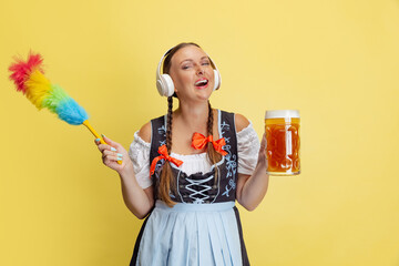 Wall Mural - Comic portrait of beautiful Oktoberfest woman, waitress wearing a traditional Bavarian or german dirndl isolated on yellow studio background.