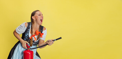 Wall Mural - Flyer with beautiful Oktoberfest woman, waitress wearing a traditional Bavarian or german dirndl screaming isolated on yellow studio background.