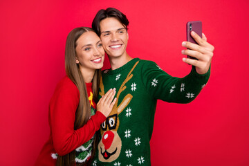 Wall Mural - Photo of glad cute couple guy hold phone shoot selfie wear ugly ornament sweater isolated red color background