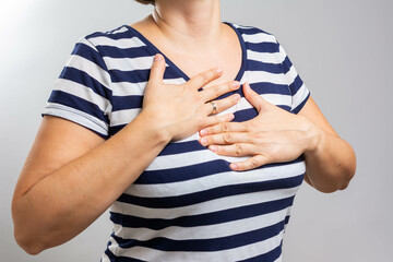 Pressure in the chest. Close-up photo of a stressed woman who is suffering from a chest pain and touching her heart area. Healthcare concept