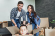 © Тарас Нагирняк - Young couple people have fun while moving to a new apartment. Parents pushes box with the son. Happy people in the new house.