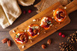 Autumn sweet potato crostini appetizers with cheese, cranberries and pecans. Above view table scene on a rustic wood background.
