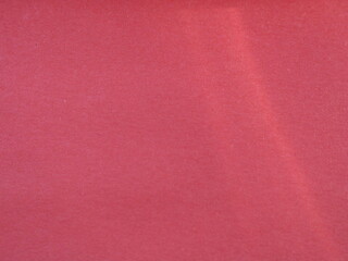 Wall Mural - Light beam on a red smooth texture, pale red background with an empty place for copying, unpleasued monochrome warm base with a sunlight line