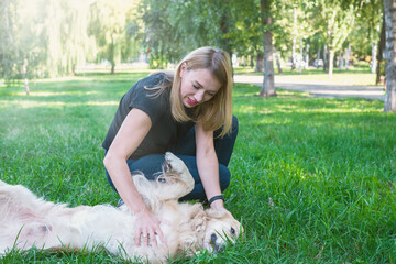 Wall Mural -  girl playing with a dog of breed golden retriever in the park