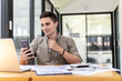 © kamiphotos - Young businessman is video call with business partner using smartphone, he talks with friends to discuss marketing plans to increase sales for the company. Concept of using technology in communication