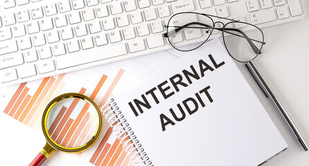 Poster - INTERNAL AUDIT text written on a notebook with keyboard, chart,and glasses