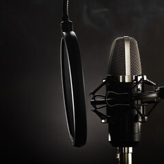 Professional studio microphone and pop filter on a dark gray background. minimalism. There are no people in the photo. Recording studio, purity of sound, music, singing, concert, radio, television.