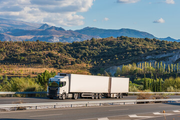 Wall Mural - Refrigerated mega-trailer truck driving on the highway with Sierra Nevada in the background.