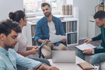 Wall Mural - Confident business team having meeting while sitting in the office together