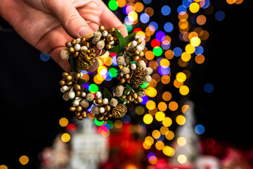 Sticker - Closeup shot of a person holding a Christmas wreath with a colorful bokeh background