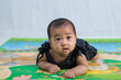 6 months old baby girl learning to crawl on the floor. Asian cute baby girl crawling on the floor with positive expression. 