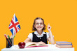 Happy smiling caucasian schoolgirl raising index finger. English lesson. Great Britain flag