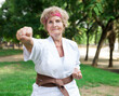 © caftor - Old lady exercising karate in park