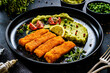 Fried fish sticks with potato and peas puree on wooden black table
