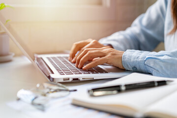 Wall Mural - Young woman sitting at living room and working on laptop at home