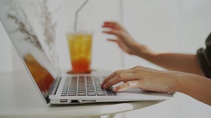 Wall Mural - Young woman sitting and working on laptop at coffee shop