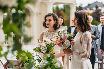 Portrait of two loving female lesbian LGBT brides telling their marriage vows at the wedding ceremony in front of wedding officiant. Shot with 2x anamorphic lens