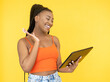 Video call. Online communication. Digital technology. Happy smiling Afro woman using PC tablet internet isolated on orange background.
