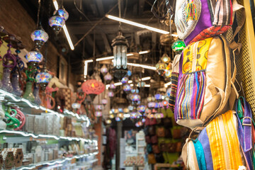 Bags hanging on the wall of a craftsmanship shop in Granada, Andalusia, Spain. On the blurred background the interior of the shop. Selective focus.