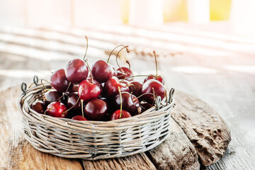 Wall Mural - cherries in a round low basket on a wooden rustic table. Ripe cherries are prepared for consumption. copy space