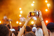 Hand with a smartphone records live music festival, Taking photo of concert stage, live concert.  Youth, party, vacation concept.