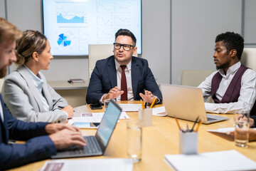 Poster - Confident coach looking at one of white collar workers during his speech at conference or training