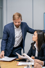 Aufkleber - Confident businessman looking at financial papers held by female colleague during discussion of data