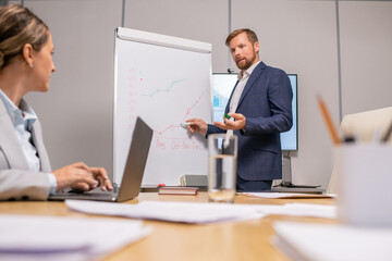 Aufkleber - Contemporary coach pointing at whiteboard at seminar while looking at businesswoman with laptop