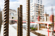 steel reinforcement for concrete reinforcement sticks out of the wall at a construction site with a house under construction blurred background.