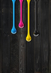 Wall Mural - cmyk ink drops on black wooden background