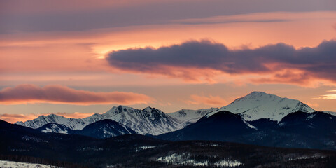 sunset behind a snow covered mountain