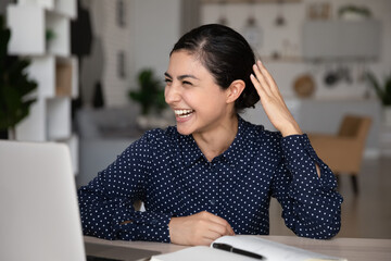 Wall Mural - Excited Indian woman laughing, looking at laptop screen, chatting online, happy smiling young female watching funny video in social network or engaged in virtual event, meeting, sitting at desk