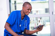 © vystekimages - young male doctor working on a digital tablet while smiling.