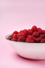 Red raspberry berry in plate on wooden table.