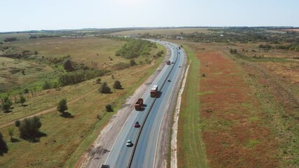 Wall Mural - Logistics cargo transportation concept. Many freight cargo trucks drive on highway among cars, aerial view.