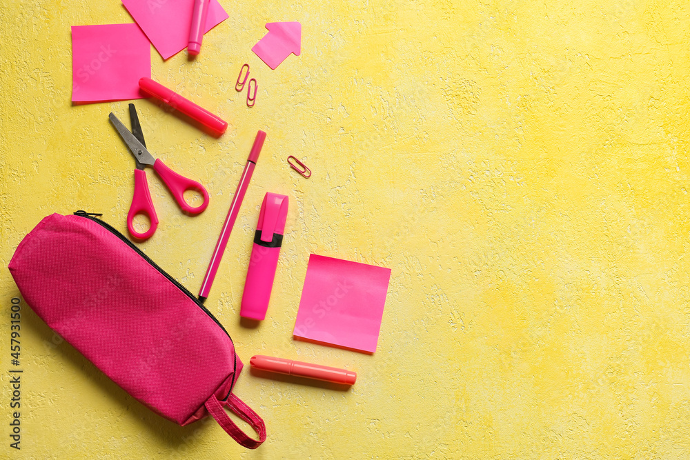 Pink pencil case and stationery on color background