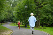 © Maria Sbytova - Little boy runs away from babysitter in summer park. Elderly grandmother trying to catch up with the child. Grandma and grandson. Difficult relationships in family