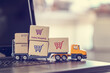 © William W. Potter - Ecommerce, online shopping and delivery service concept : Boxes with shopping carts on a trailer truck on a laptop, depicts e-commerce impacts the trucking industry that retailer needs fast, low price