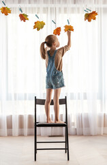 Wall Mural - child making a garland of yellowed leaves