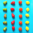 Chewing gum in the form of pear, orange, strawberry and lemon on a blue background are laid out in rows. Bright fruit candy top view.