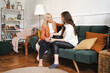 © diignat - Mother and adult beautiful daughter having fun enjoying talk sit on sofa in modern living room at home