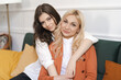 © diignat - Beautiful mother and adult daughter hugging portrait close up, sitting on couch at home, smiling woman embracing mum, spending leisure time together, two generations good relationship